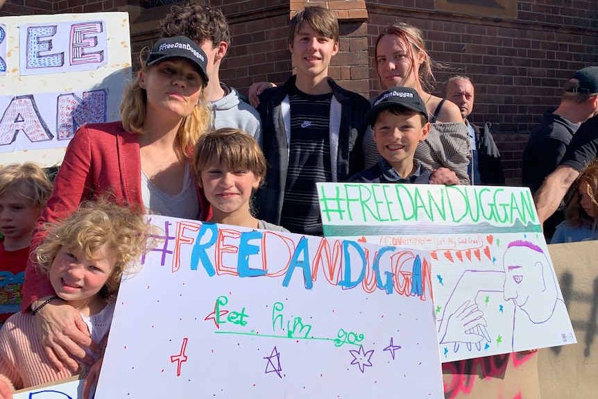 Saffrine Duggan and her children hold signs