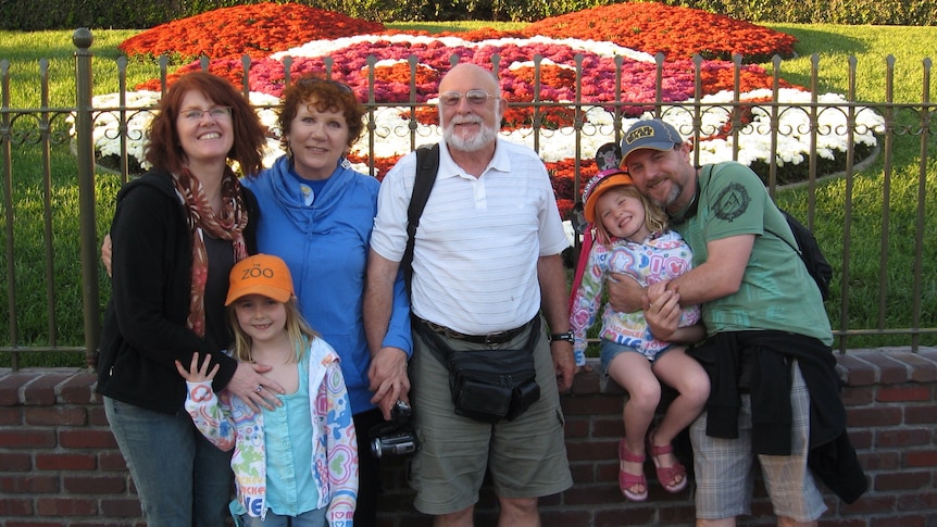 A family photo of six people outside Disneyland
