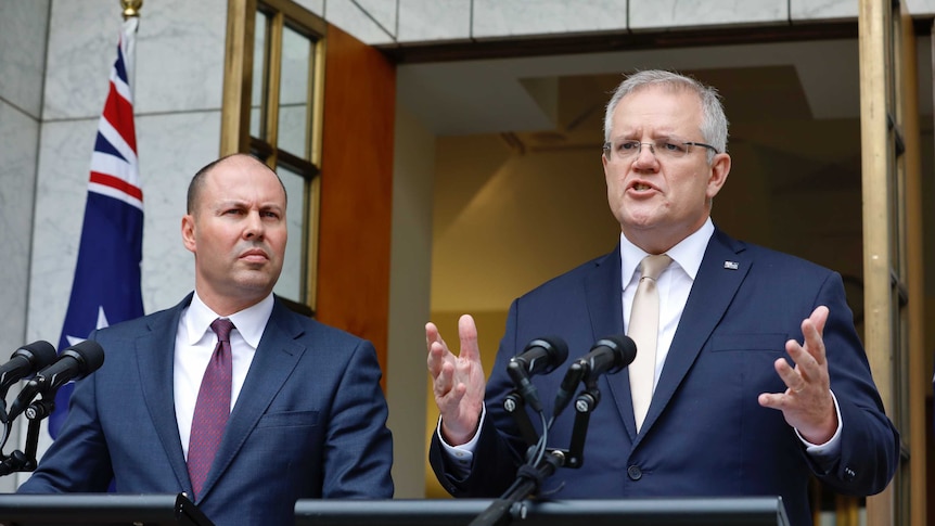 Josh Frydenberg and Scott Morrison stand at podia with an Australian flag behind them