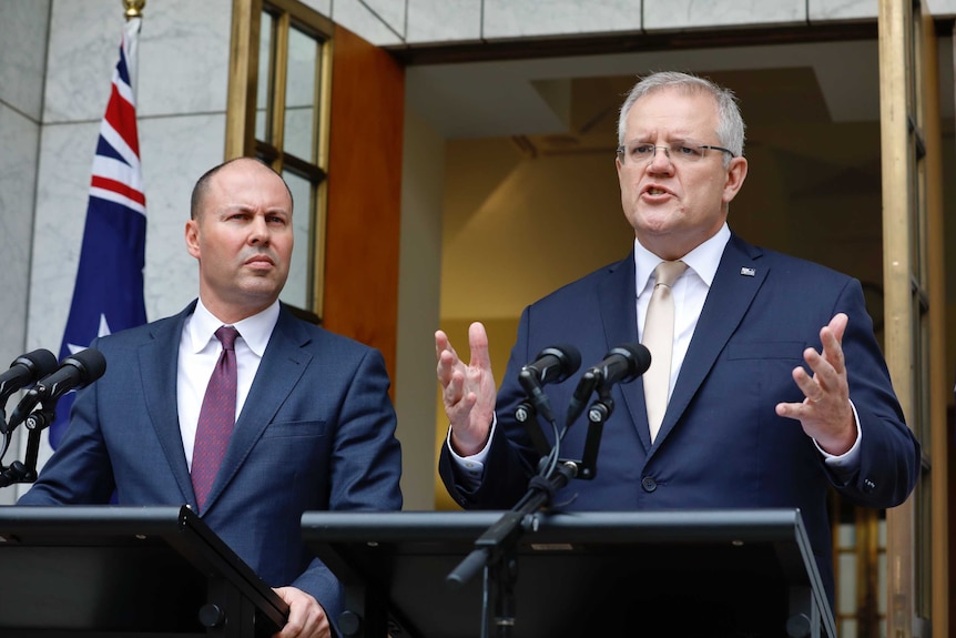 Josh Frydenberg and Scott Morrison stand at podia with an Australian flag behind them