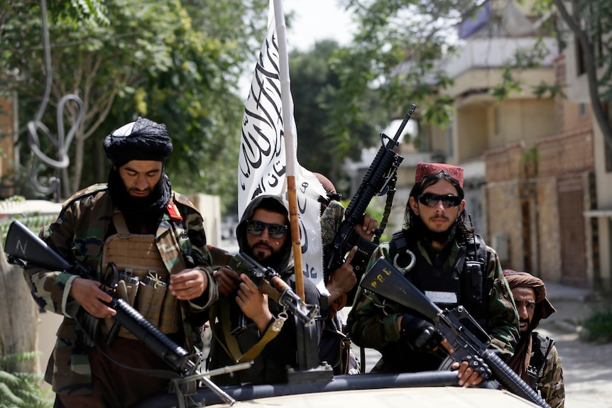 Taliban fighters display their white flag on patrol in Kabul