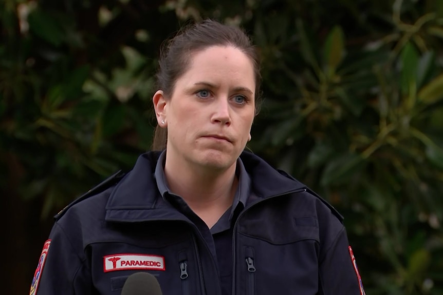 A woman in a paramedic outfit in front of bushes