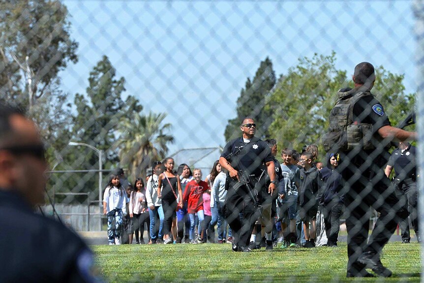 A police officer leads students outside after a shooting at a San Bernardino school