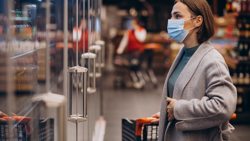 A woman wearing face mask shopping at a grocery store