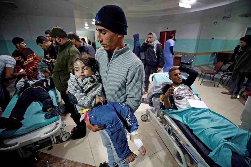 A Palestinian man carries his wounded daughter following Israeli airstrikes on nearby militant targets in Gaza.
