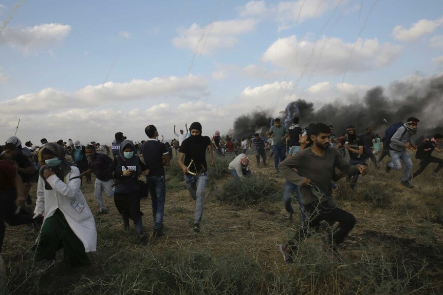 Men and women are seen running surrounded by smoke and tear gas bombs.
