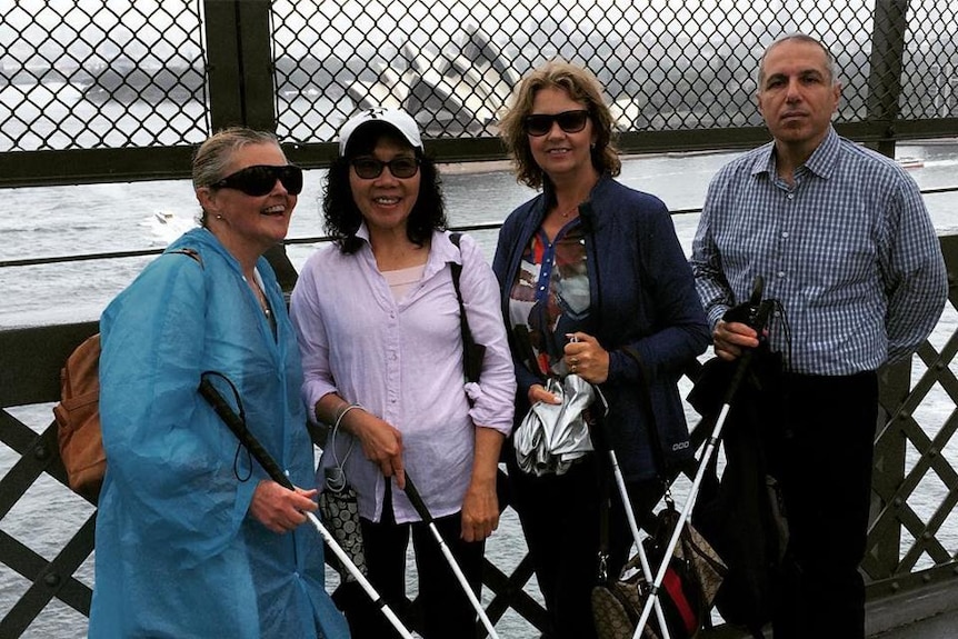 A group of smiling tourists on a wet day in Sydney Harbour.