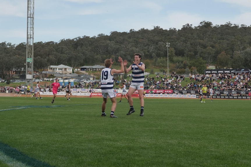 two men on footy oval high five