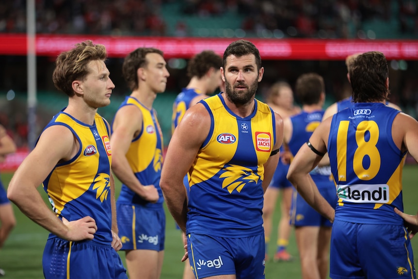 West Coast players stand silently staring across the ground after a big loss.