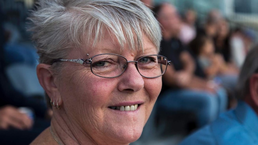 a woman sitting in the stands smiling at the camera