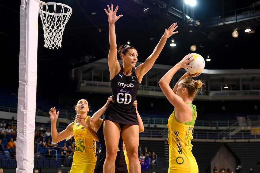 An Australian netballer lines up her shot as a New Zealand defender leaps to block her in a Test.