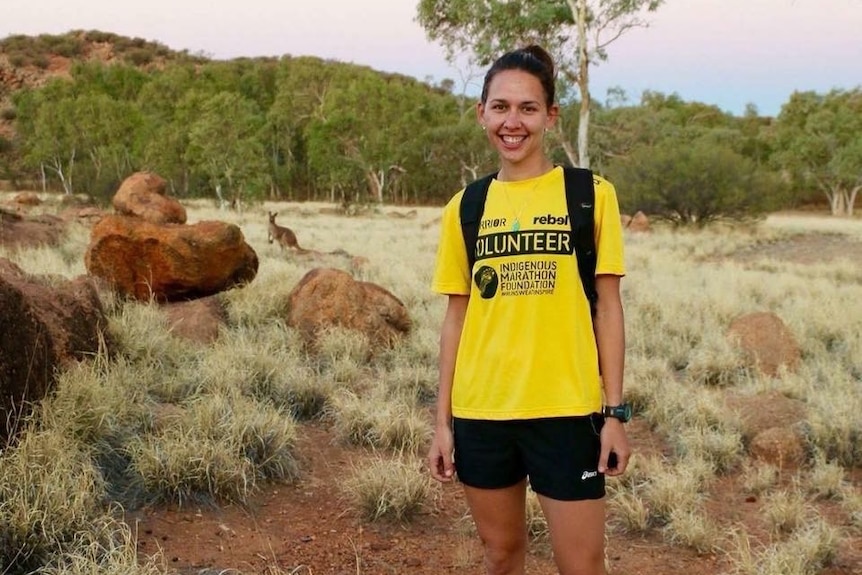 Athlete and running coach stands in front of camera in outback Australia setting.