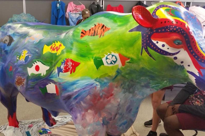 Cow statue painted by schoolchildren with fish designs showing flags of the world, including Taiwan flag.