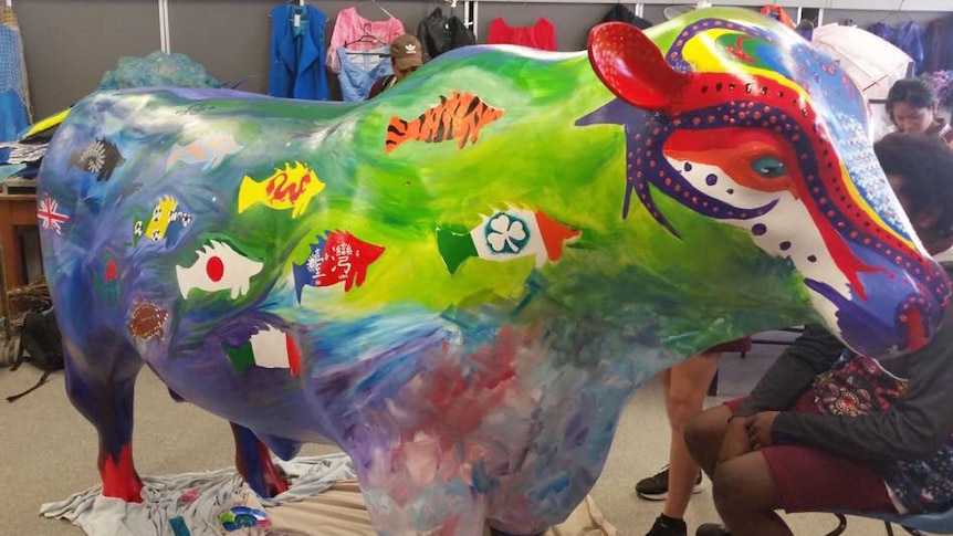 Cow statue painted by schoolchildren with fish designs showing flags of the world, including Taiwan flag.