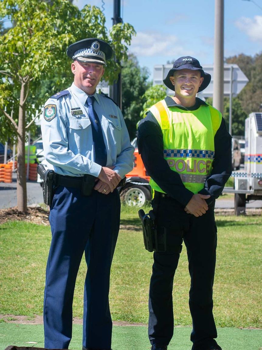 two men in police uniform stand next to each other in front of tents