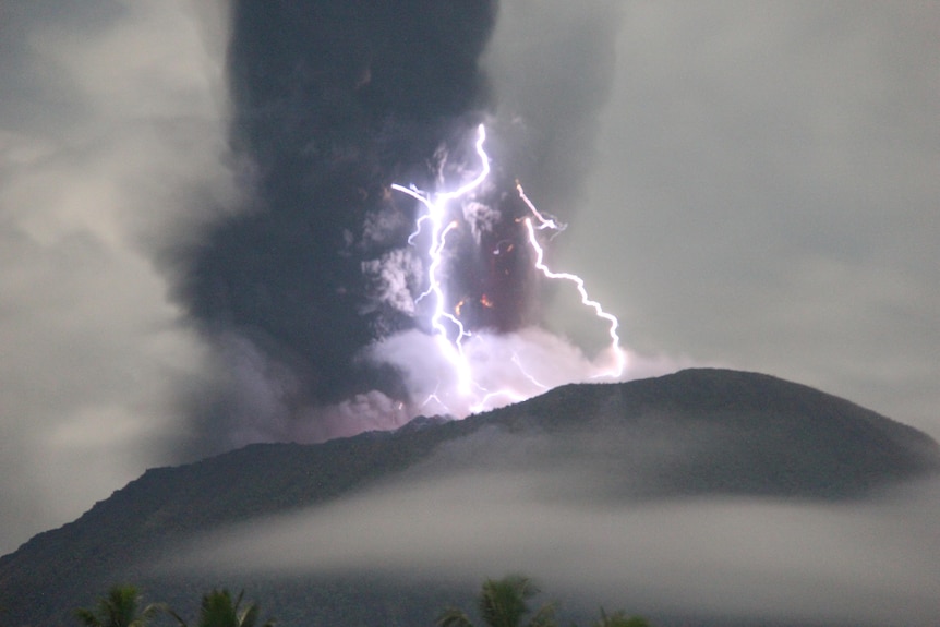 Lightning appears amid a storm as Mount Ibu spews volcanic material during an eruption.