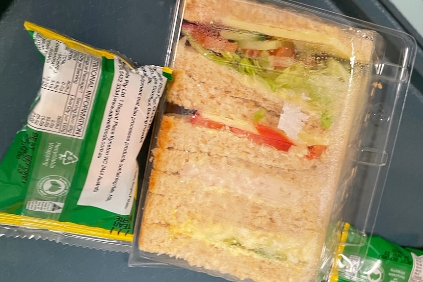A photo of a pre-packaged sandwich sitting next to a packet of biscuits wrapped in green plastic
