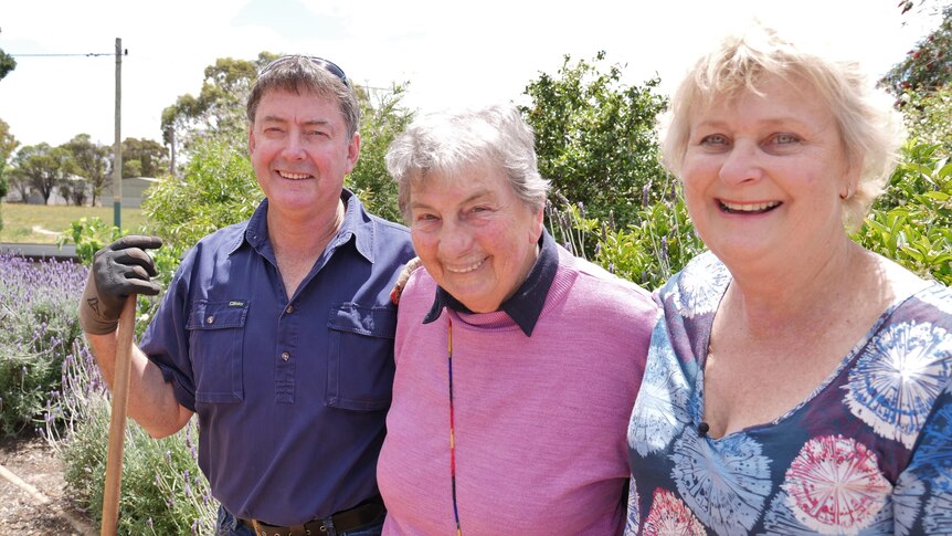 A middle aged man and woman help an older lady prune lavender.
