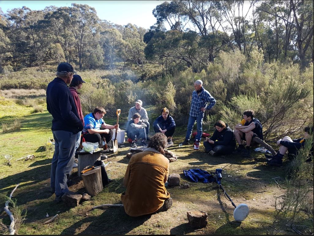 A group of women and men gather around a campfire