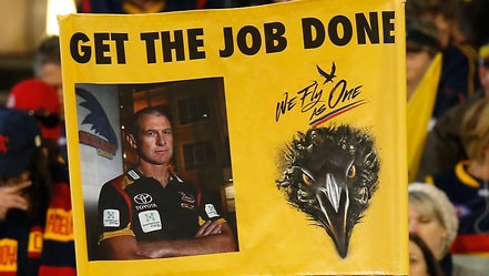 Crows fans hold up a banner of Phil Walsh with the words 'get the job done'