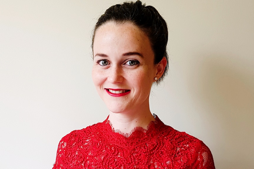 A head shot of Laura Smith-Khan who wears a red top and lipstick