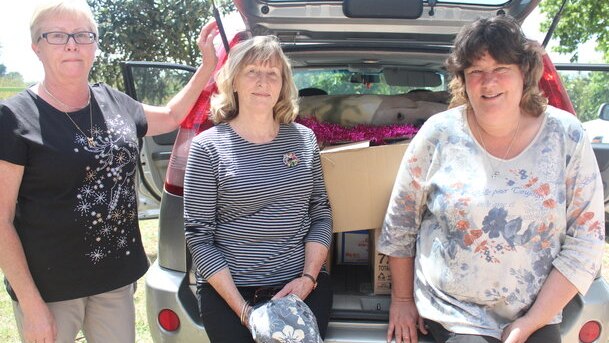 Gippsland Farmer Relief volunteers sit in front of a car loaded with boxes.