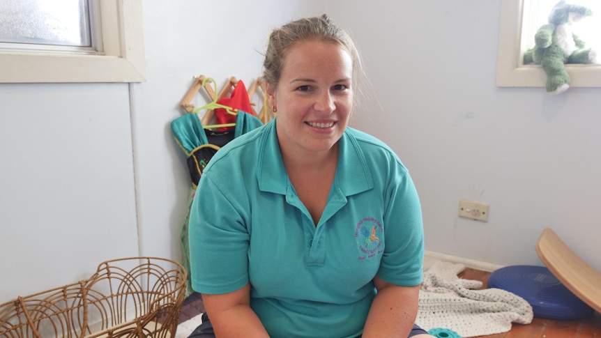 A woman wearing a green polo shirt smiles at the camera