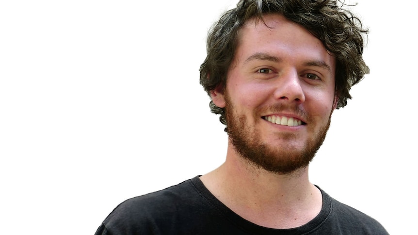 A profile shot of a young man with curly brown hair and a beard.