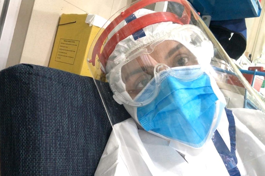 A woman in full PPE lying on an ambulance stretcher