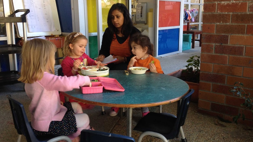 Children sit at a table eating lunch with a childcare worker at C and K childcare centre in Brisbane