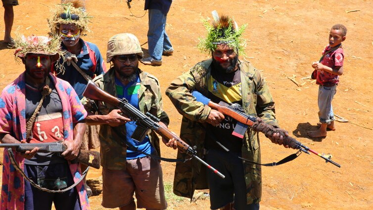 Armed members of a clan pose in camouflage and brandishing riffles.