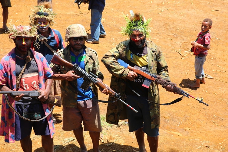 Armed members of a clan pose in camouflage and brandishing riffles.