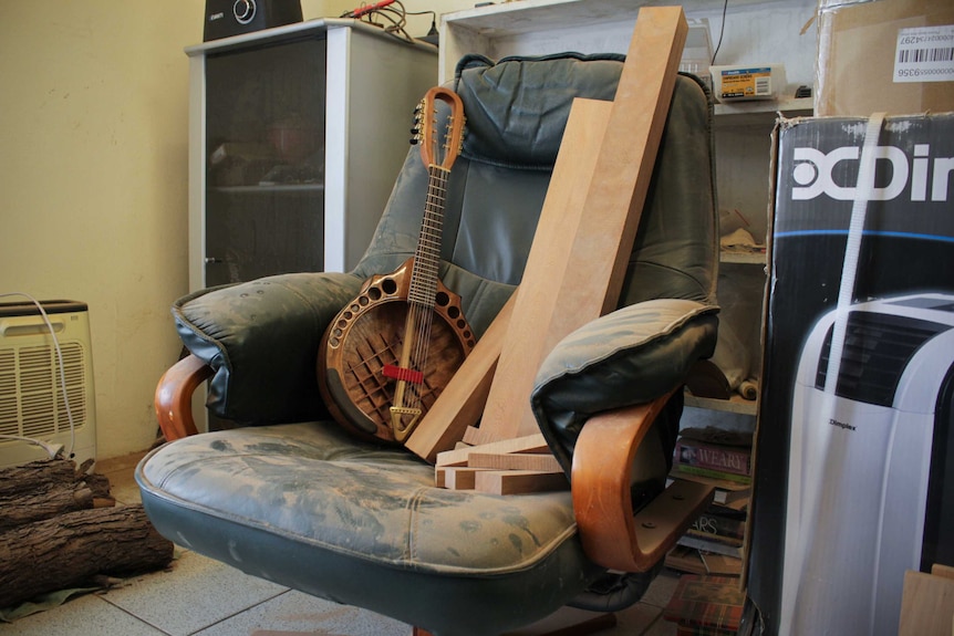 A half-made made mandolin sitting on a dusty chair.