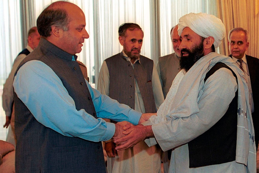 The Taliban's new interim prime minister clasps hands with the then-prime minister of Pakistan in this file photo from 1999.