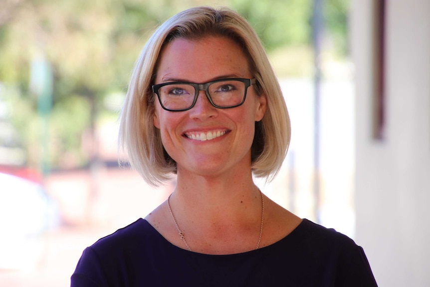 A head and shoulders shot of a smiling Hannah Beazley wearing spectacles outdoors.