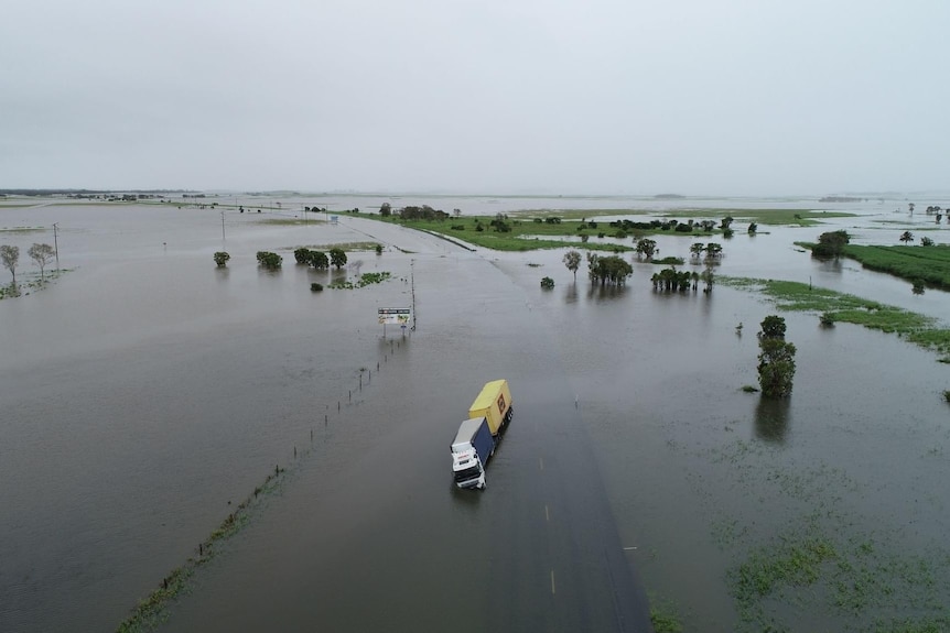 A truck half tipped over in flood waters.