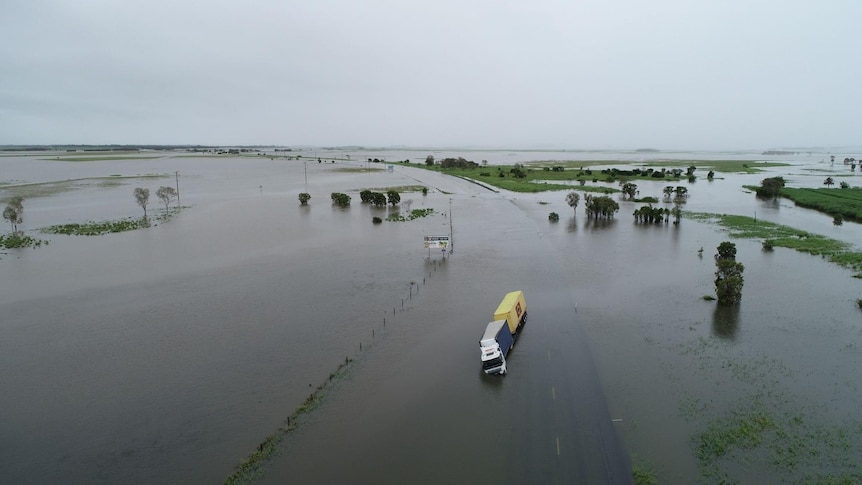 A truck half tipped over in flood waters.