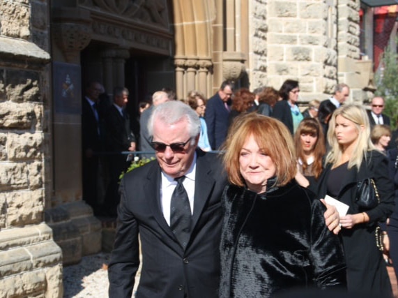 Dallas Dempster has his arm around Eileen Bond as they leave Alan Bond's funeral