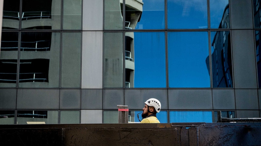 A construction worker in a hardhat poking his head above a barrier