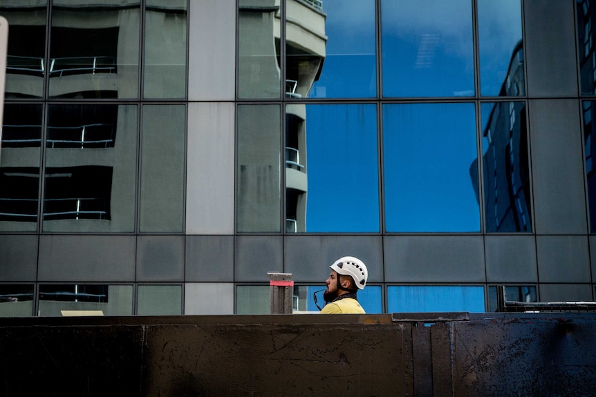 A construction worker in a hardhat poking his head above a barrier