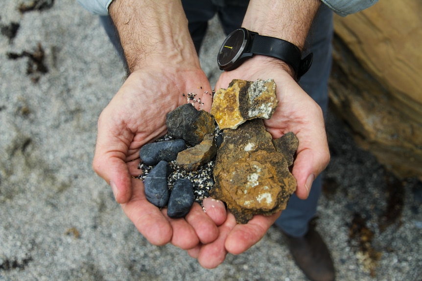 A man's hands holding rocks.