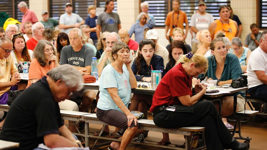 Evacuated residents hold a prayer before the start of a community meeting.