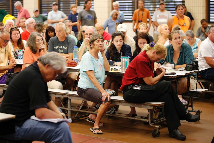 Displaced residents hold a prayer before the start of a community meeting.