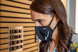 New Zealand Prime Minister Jacinda Ardern wearing a black face mask which reads New Zealand