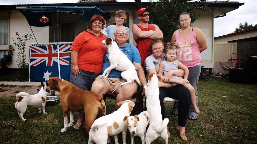 The Ashley family sit in the front yard with their dogs.