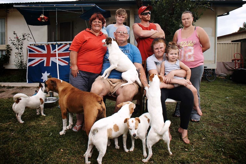 The Ashley family sit in the front yard with their dogs.