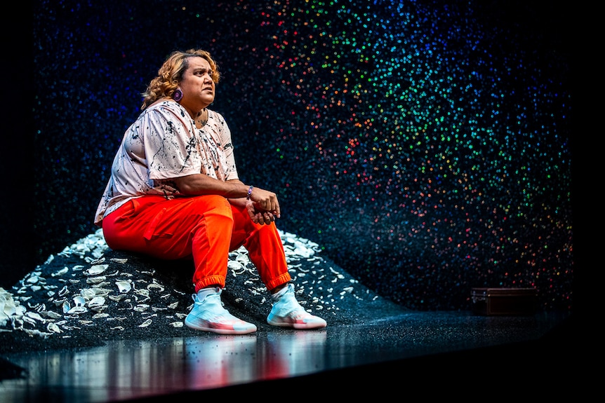 Elaine Crombie sits on a mound of dirt scattered with midden shells in The 7 Stages of Grieivng