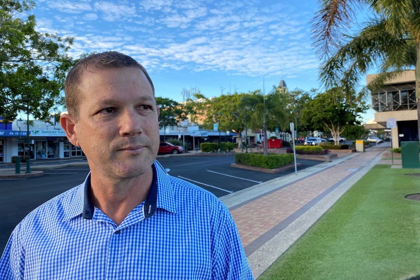 Man wearing blue and white check shirt stands in Bundaberg's main street.