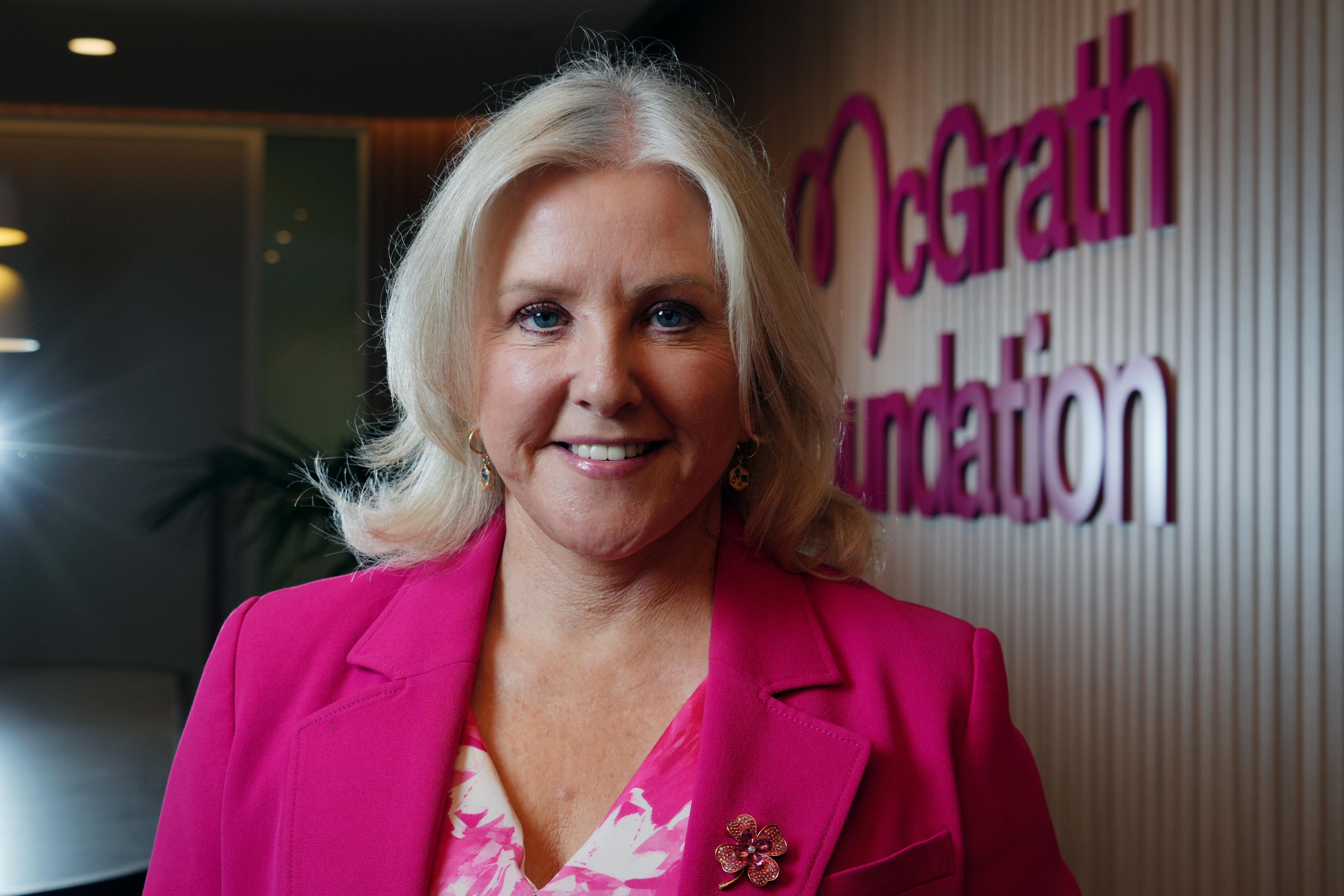 middle aged blonde woman wearing pink smiling