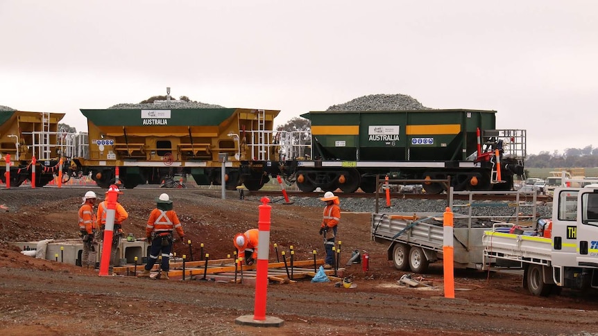 Men in high-visibility clothing work near a rail line.